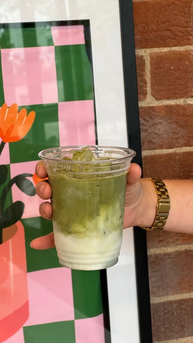 Iced matcha latte held in front of a checkerboard print